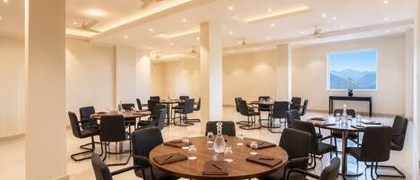 A conference room with multiple tables, chairs, ceiling fans, and recessed lighting.