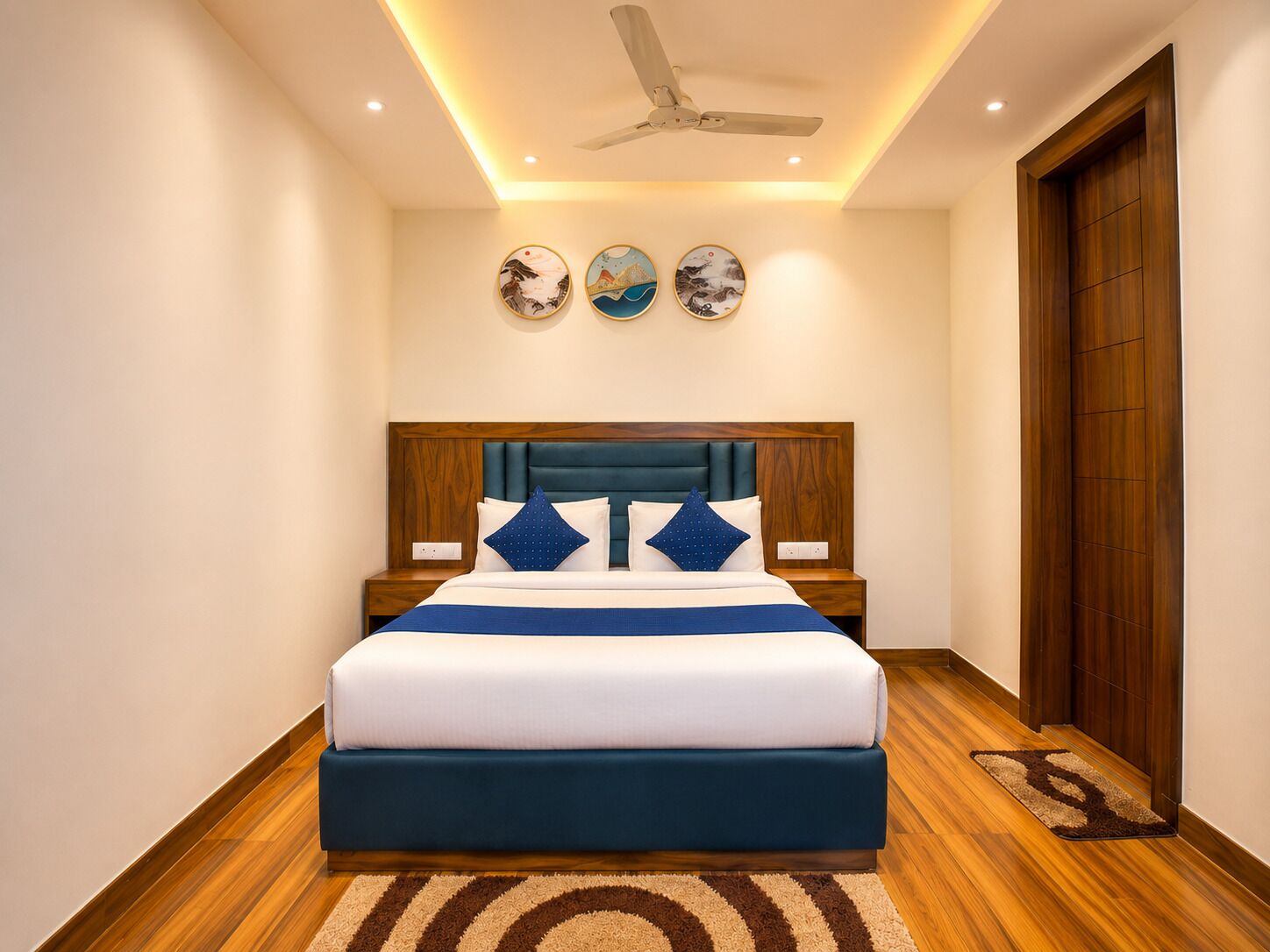 Una habitación de hotel moderna con una cama grande, cabecera de madera y ventilador de techo.