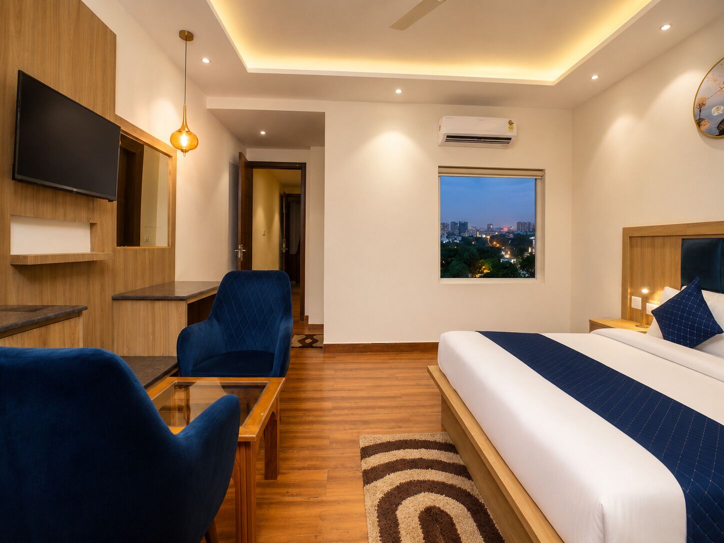 Ein modernes Hotelzimmer mit Bett, Schreibtisch, Stuhl, Fernseher und Fenster mit Blick auf die Stadt.