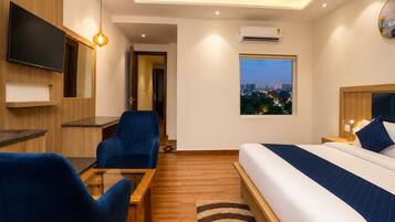 A modern hotel room with a bed, a desk, a chair, a TV, and a window with a city view.