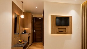 Ein modernes Interieur mit Holzboden, integriertem Fernseher, Kaffeemaschine und Obstschale auf einer Arbeitsfläche.