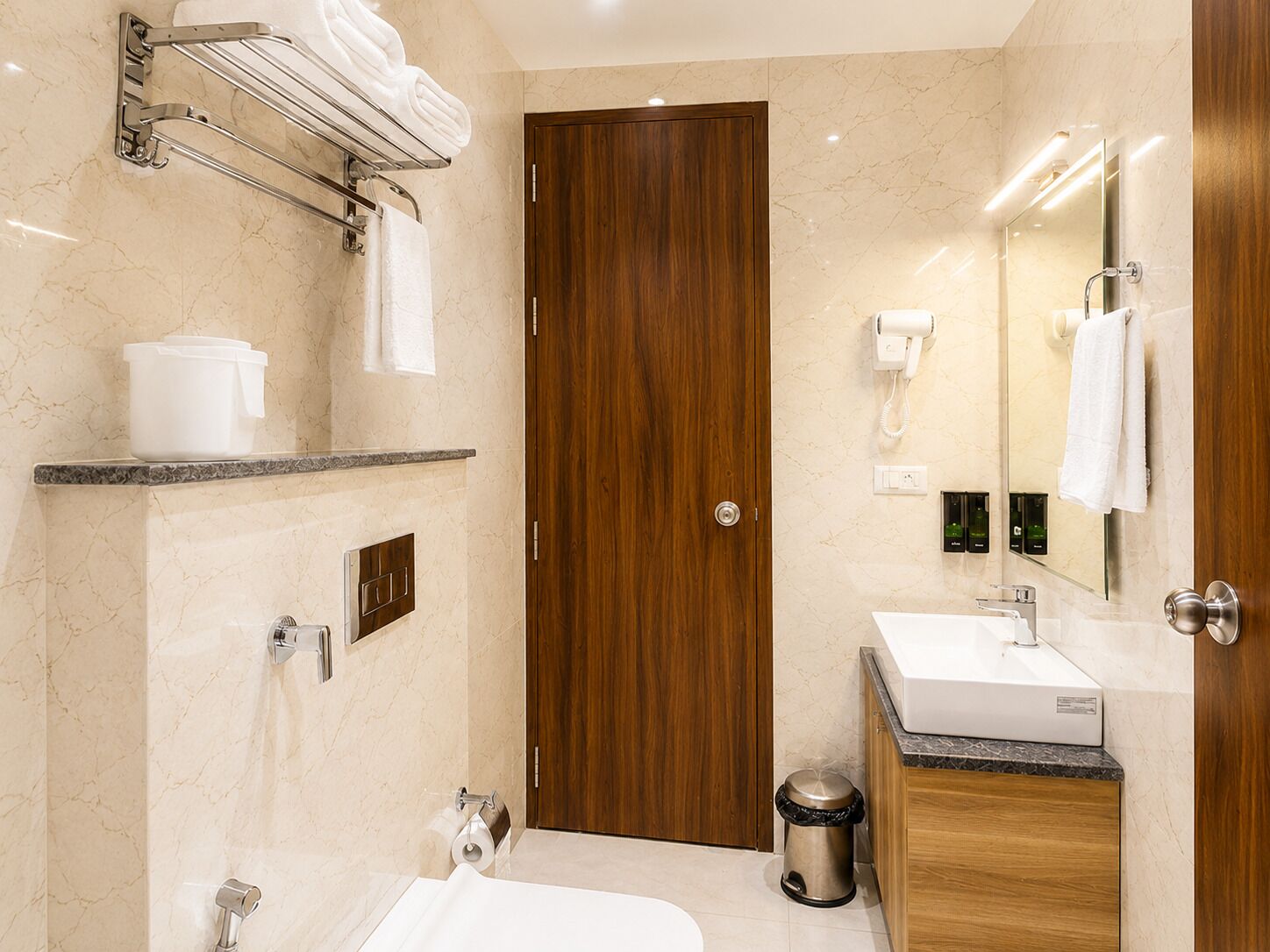 A modern bathroom with a wooden door, a sink, a mirror, and a towel rack.