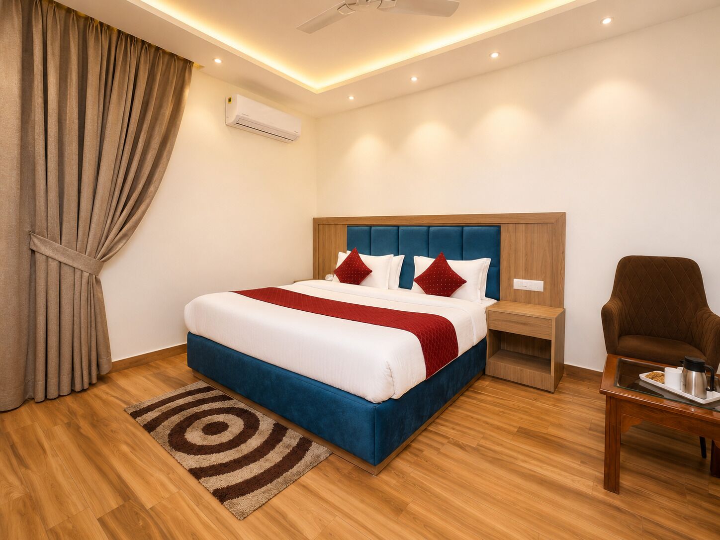 A hotel room with a bed, a nightstand, a chair, a coffee table, and an air conditioning unit.