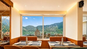 Ein Restaurant mit Terrasse und Bergblick, mit Holztischen und blauem Himmel.
