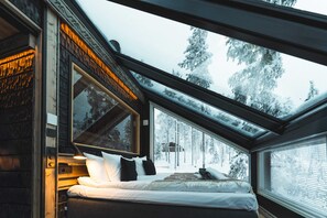 A bedroom with a large window, a bed, and a view of snow-covered trees. - Suomu Aurora Glass Resort (Kemijarvi)