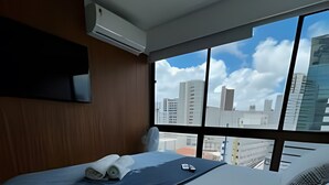 Hotellihuone, jossa on sänky, ikkuna ja näkymä kaupungin ylle.