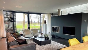 Una sala de estar moderna con sofá, sillas, una mesa de centro, televisor y chimenea.