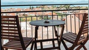 Un balcón con una mesa y dos sillas, con vistas a una zona residencial con casas y montañas a lo lejos.