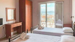Un dormitorio con techo de madera, una cama, un escritorio, un armario y un balcón con vistas.