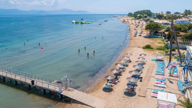 Una playa con un muelle, sombrillas y sillas reclinables.