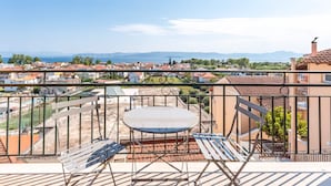 Een balkon met een tafel en stoelen, met uitzicht op een woonwijk en een waterpartij.