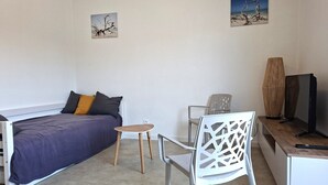 A bedroom with a bed, a small table, a chair, a TV, and two wall art pieces. - The "Le Cosy" Apartment – Shared Pool (La Tranche-sur-Mer)