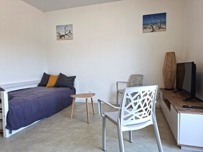 A bedroom with a bed, a small table, a chair, a TV, and two wall art pieces. - The "Le Cosy" Apartment – Shared Pool (La Tranche-sur-Mer)