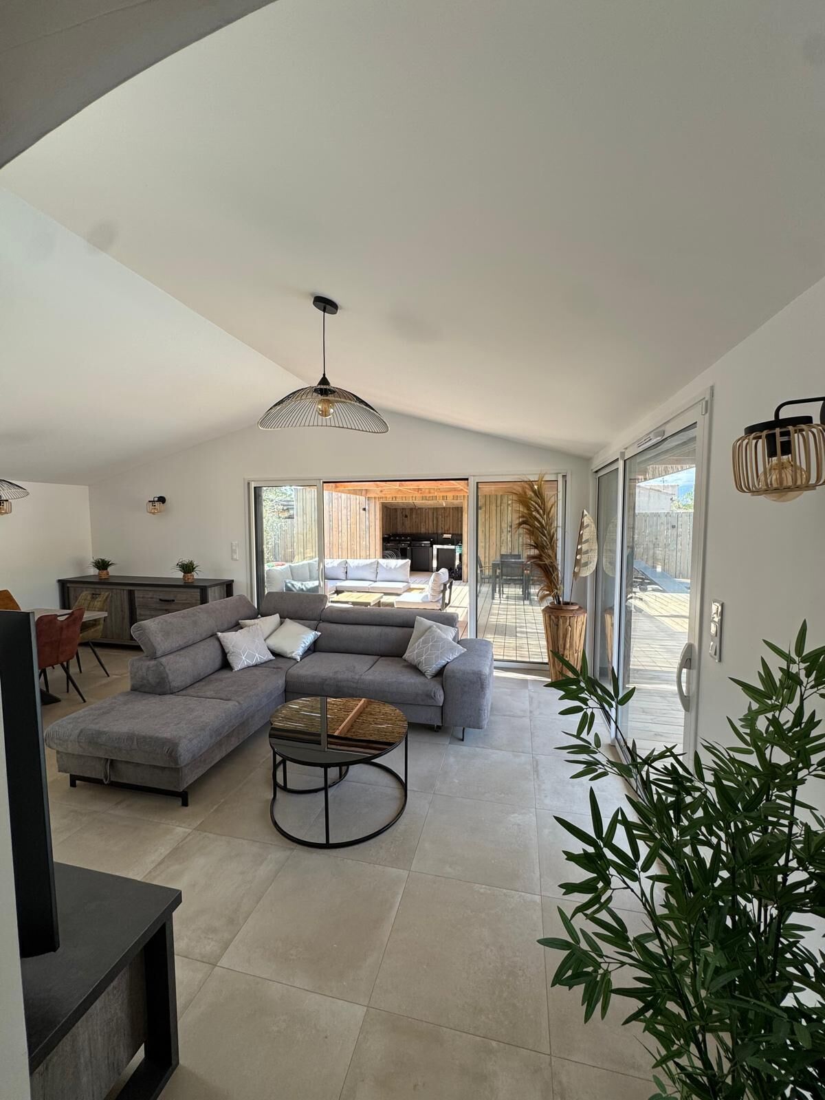 A modern living room with a sectional sofa, a coffee table, and a dining area with a table and chairs.