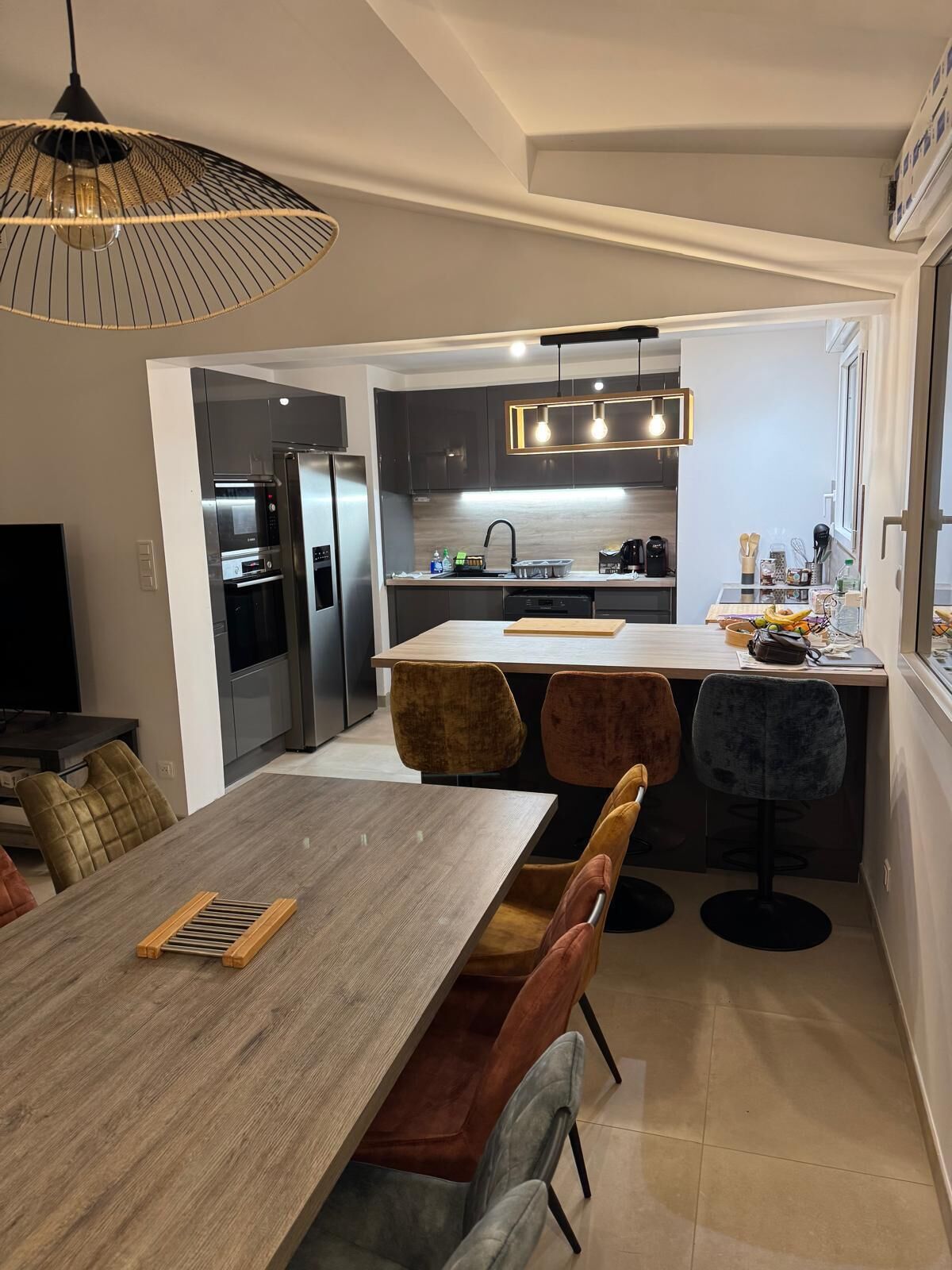 Una cucina moderna con isola centrale, elettrodomestici integrati e zona pranzo con tavolo in legno e sedie imbottite.