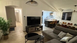 Ein modernes Wohnzimmer mit Sofa, Fernseher und Essbereich.