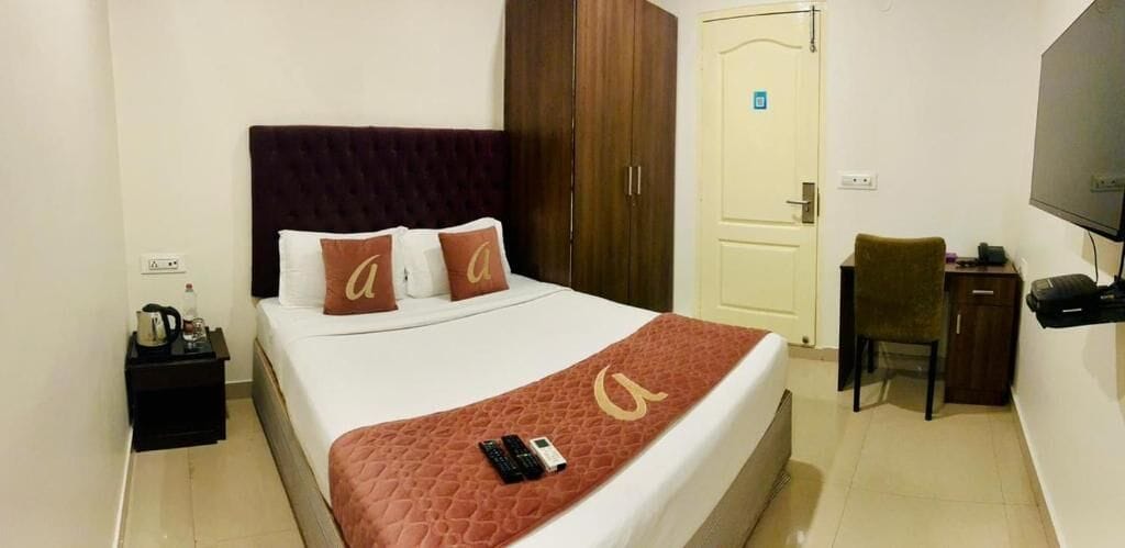 A hotel room with a bed, a desk, a chair, a television, and a wardrobe.