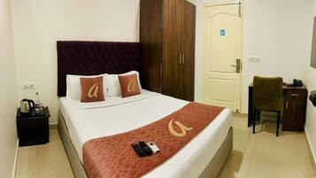 A hotel room with a bed, a desk, a chair, a television, and a wardrobe.