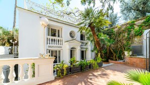 A white building with a balcony, potted plants, and a palm tree. - Muta House (Sorrento)