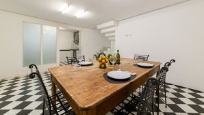 A dining area with a wooden table, black and white checkered floor, and metal chairs. - Muta House (Sorrento)