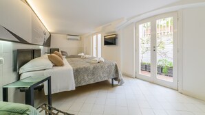 A bedroom with a bed, a TV, a desk, and a window with a view of the outside. - Muta House (Sorrento)