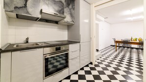 A kitchen with a black and white checkered floor, a stainless steel sink, a built-in oven, and a wall-mounted range hood. - Muta House (Sorrento)