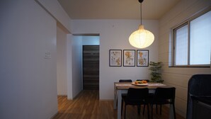 Un comedor con una mesa, sillas, una lámpara colgante y cuadros en la pared.