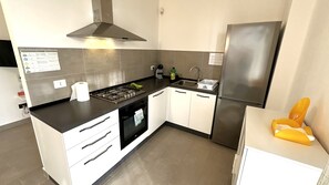 Eine moderne Küche mit Gasherd, Backofen, Edelstahlkühlschrank und weißen Schränken.