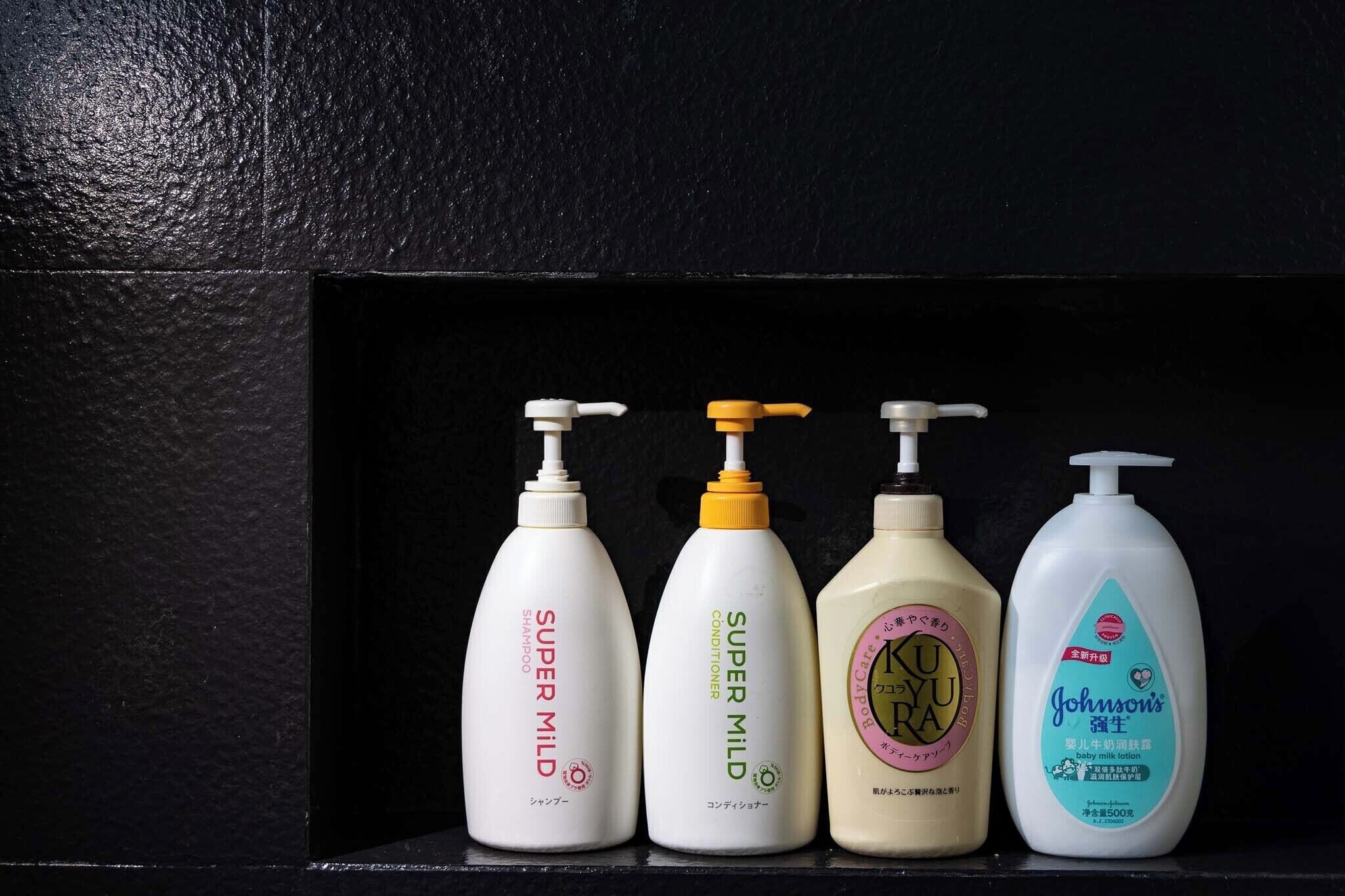 Fyra flaskor med produkter för personlig hygien står på en hylla.