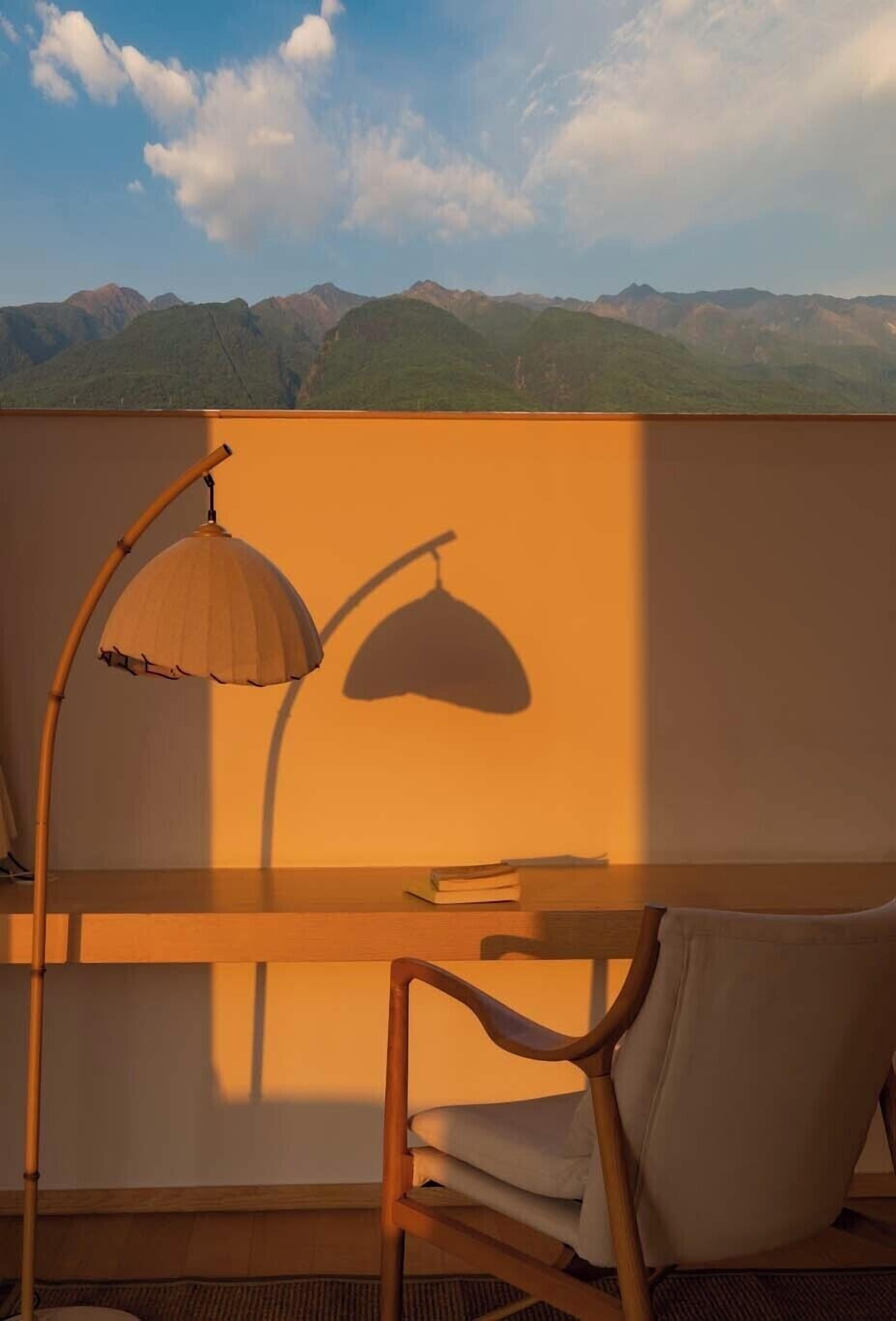 A room with a desk, chair, and a lamp casting a shadow on the wall.