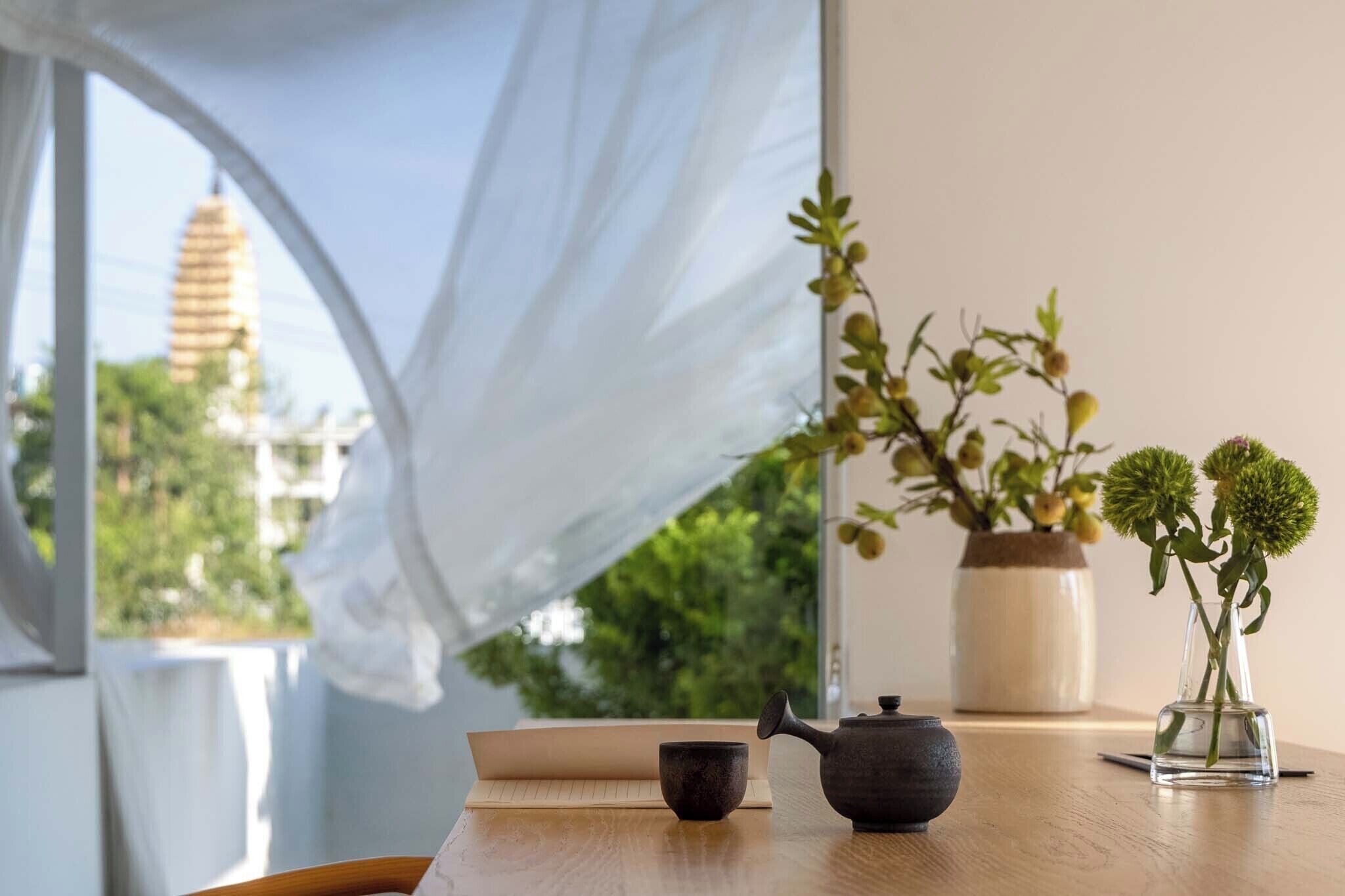 A table with a teapot, a cup, and a vase with flowers.