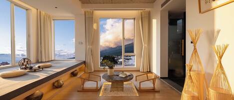 Un interior moderno con un amplio ventanal, una mesa de piedra y vistas a un paisaje montañoso.