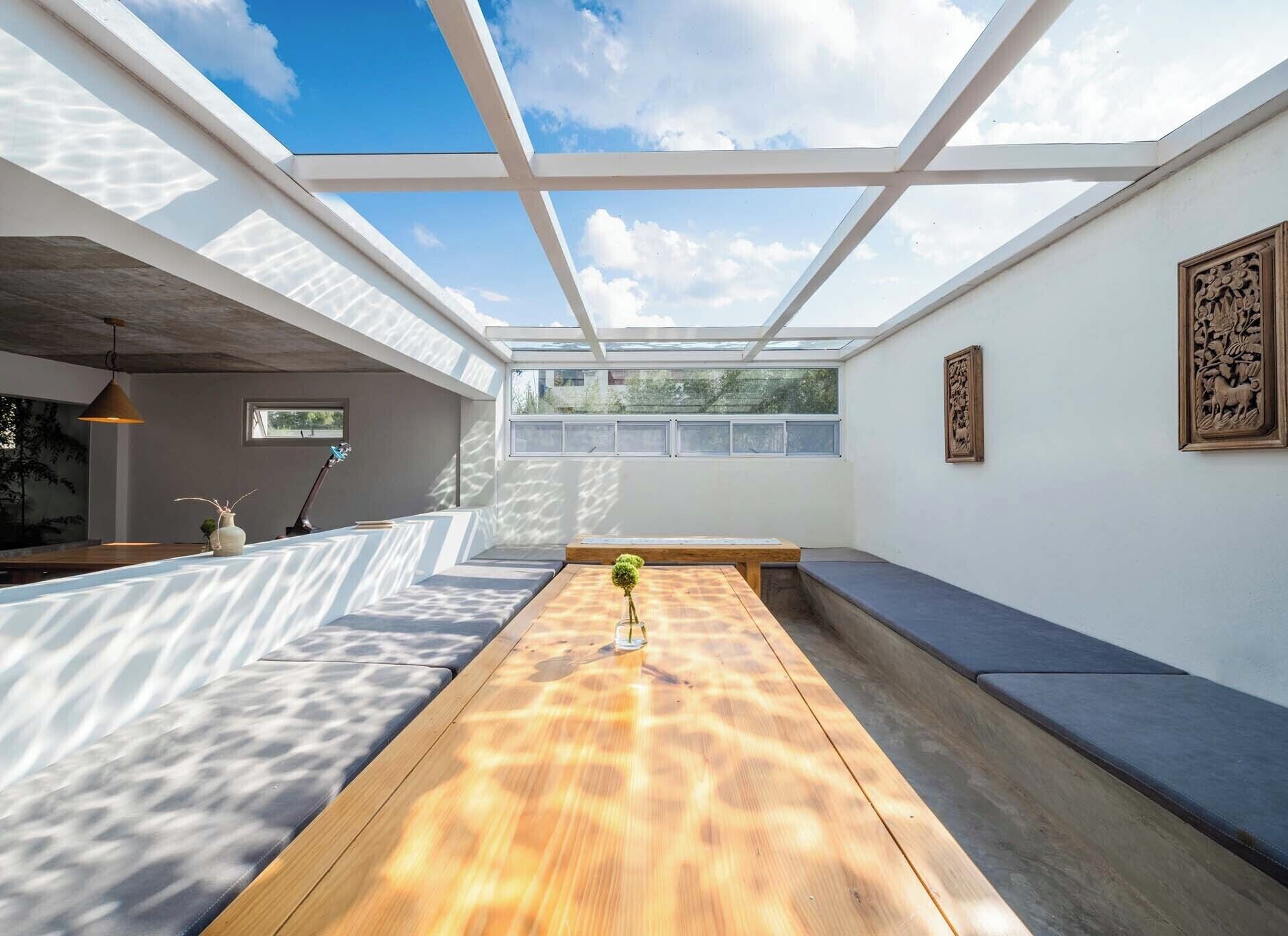 Un interior moderno con una mesa de madera, asientos y un tragaluz.