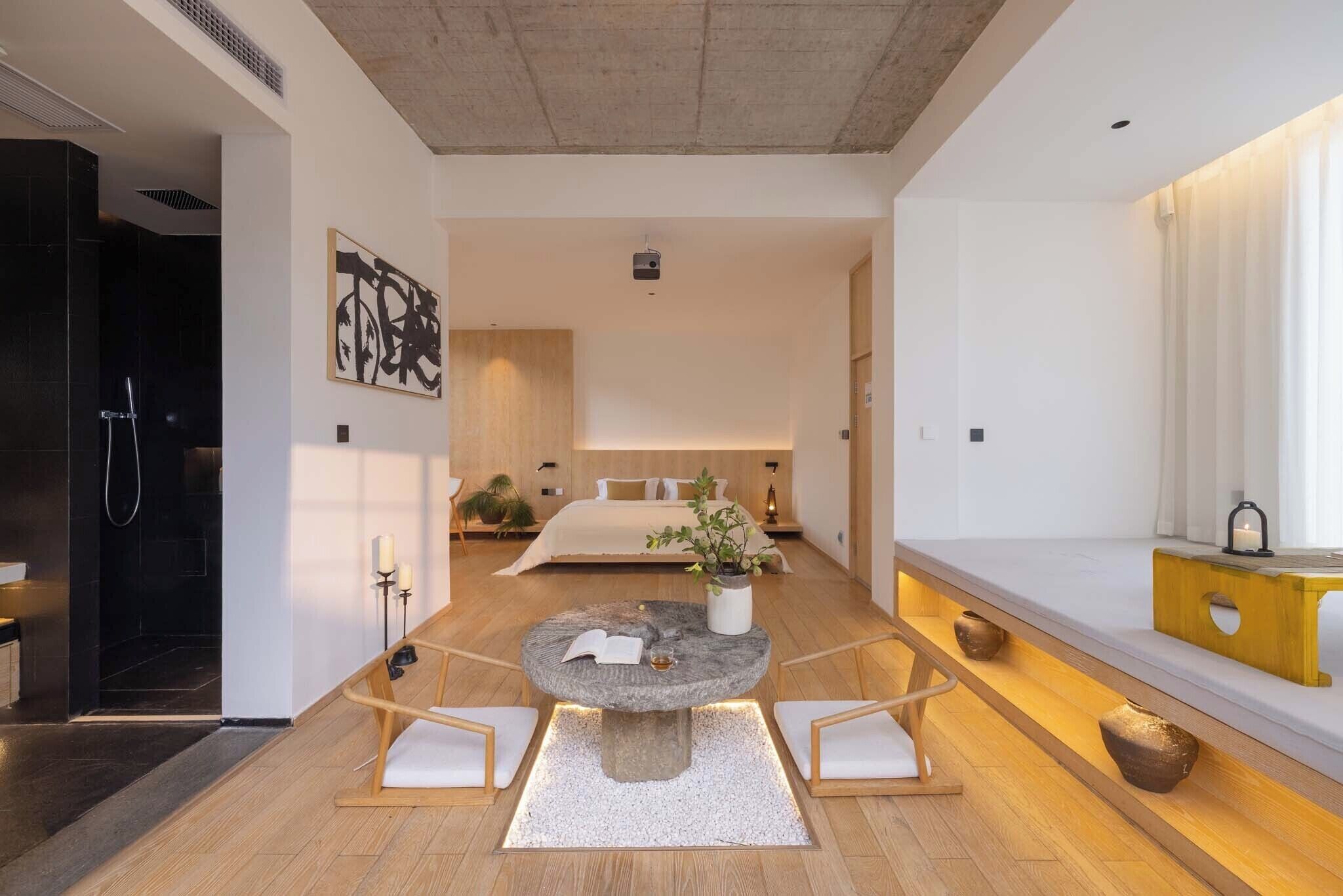 Een moderne hotelkamer met een groot bed, een ronde tafel met stoelen, een klein plantje en een houten consoletafel.