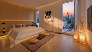 Une chambre moderne avec un grand lit, des lampes de chevet, une vue sur le coucher de soleil et une grande fenêtre.