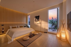 Un dormitorio moderno con una cama grande, lámparas de noche, vistas al atardecer y un ventanal amplio.