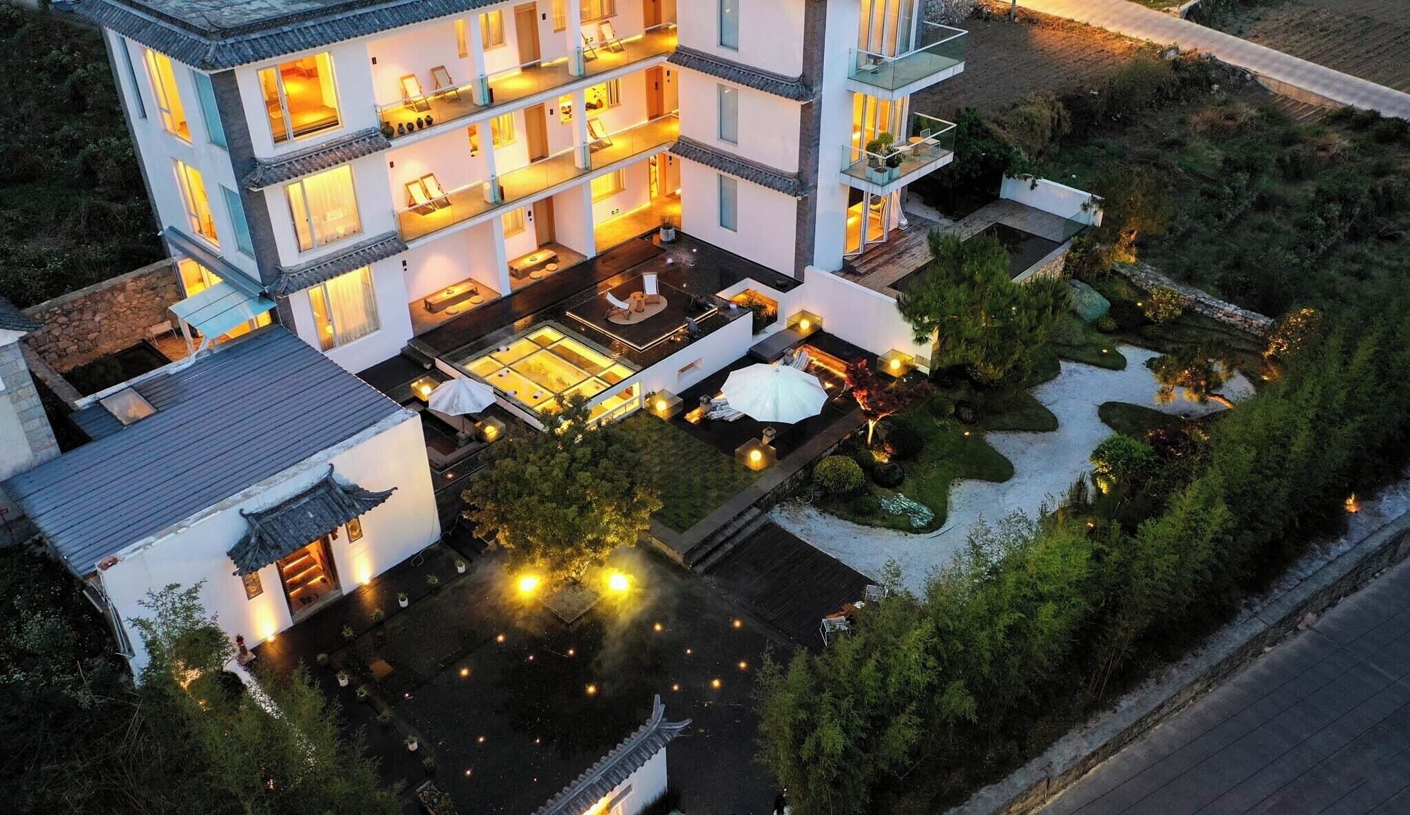 A multi-story hotel with balconies, a rooftop terrace, and a landscaped garden.