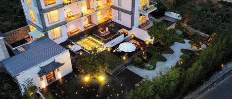 A multi-story hotel with balconies, a rooftop terrace, and a landscaped garden.