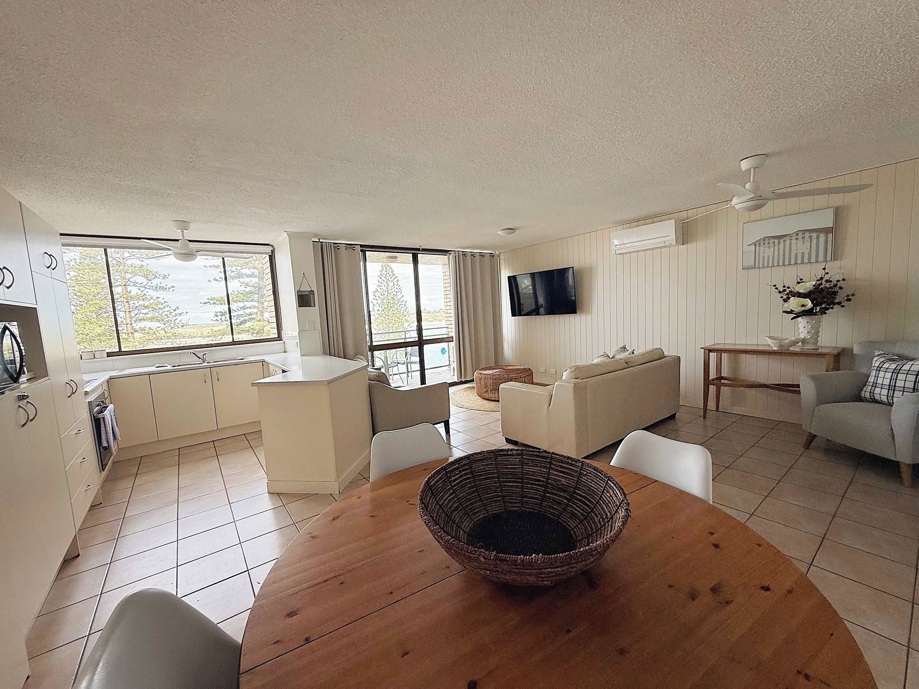 A modern living room with a dining table, sofa, and TV.