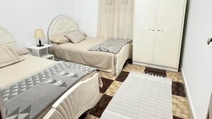 Un dormitorio con dos camas, un armario, una mesita de noche y una lámpara.