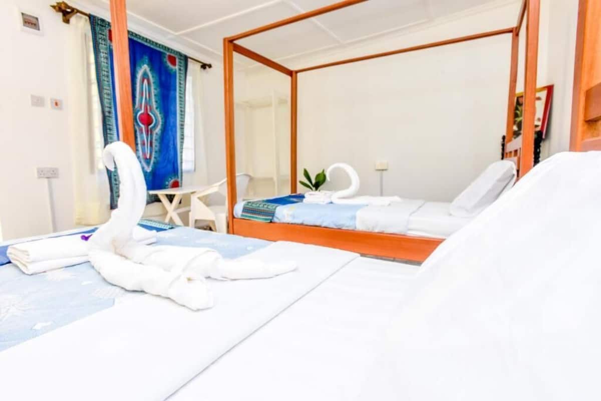 Una cama con dosel y una toalla con forma de cisne, junto con un edredón azul.
