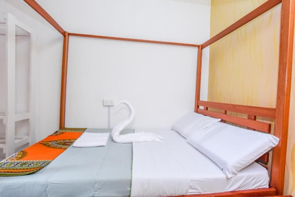 Un lit simple avec une tête de lit en bois, du linge de lit blanc et une serviette décorative.