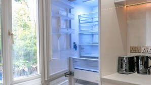 Una cocina moderna con refrigerador integrado, una ventana y una encimera con dos tostadoras.