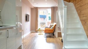 Un interior moderno con una escalera, una zona de estar y vistas a través de una ventana.