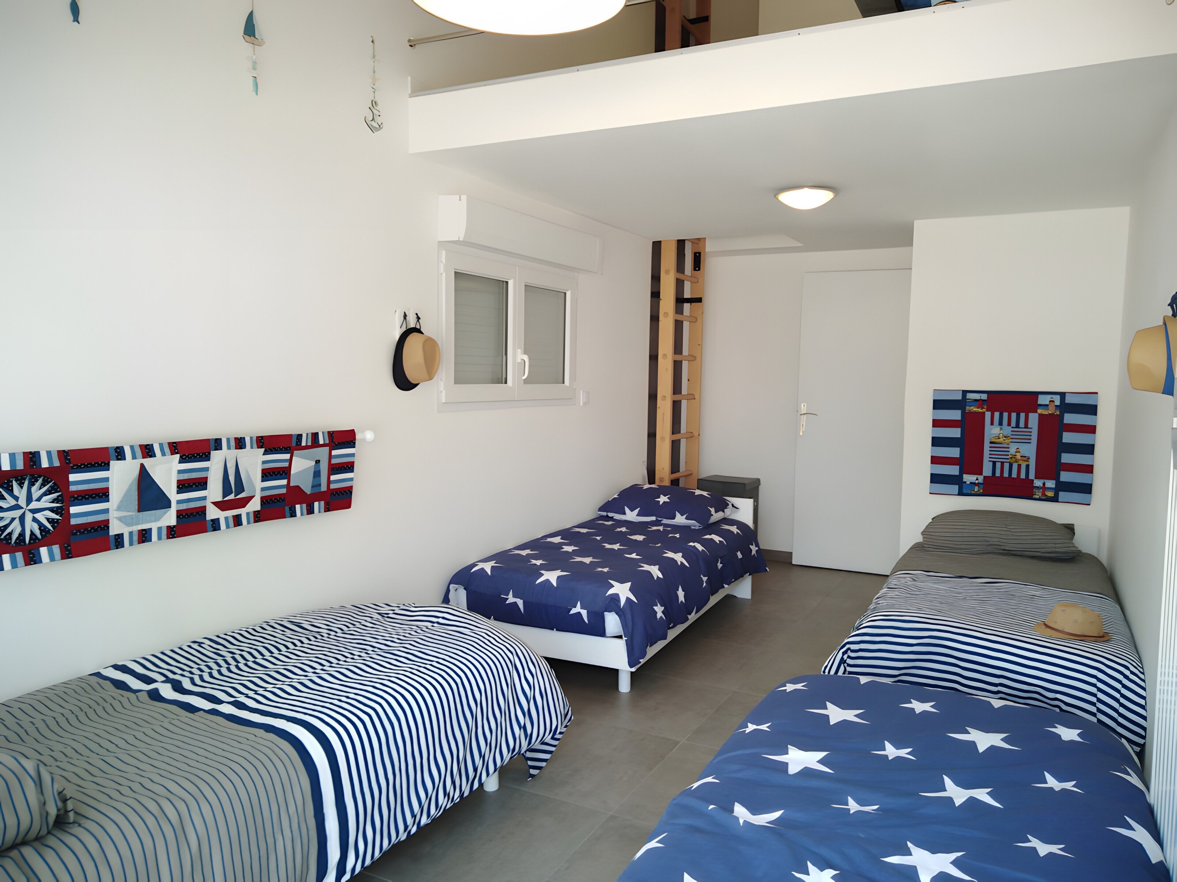 Une chambre avec deux lits simples, une armoire, une fenêtre et une porte.
