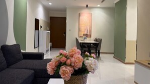 Ein modernes Wohnzimmer mit einer Couch, einem Essbereich mit Tisch und Stühlen sowie einer dekorativen Vase mit Blumen.