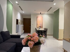 A modern living room with a sofa, a dining area with a table and chairs, and a decorative vase with flowers. - 2 Bedroom Apartment for Rent at Vinhomes Central Park (Thành phố Hồ Chí Minh)