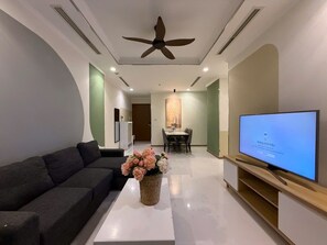 A modern living room with a sofa, a flat-screen TV, a ceiling fan, and a dining area in the background. - 2 Bedroom Apartment for Rent at Vinhomes Central Park (Thành phố Hồ Chí Minh)