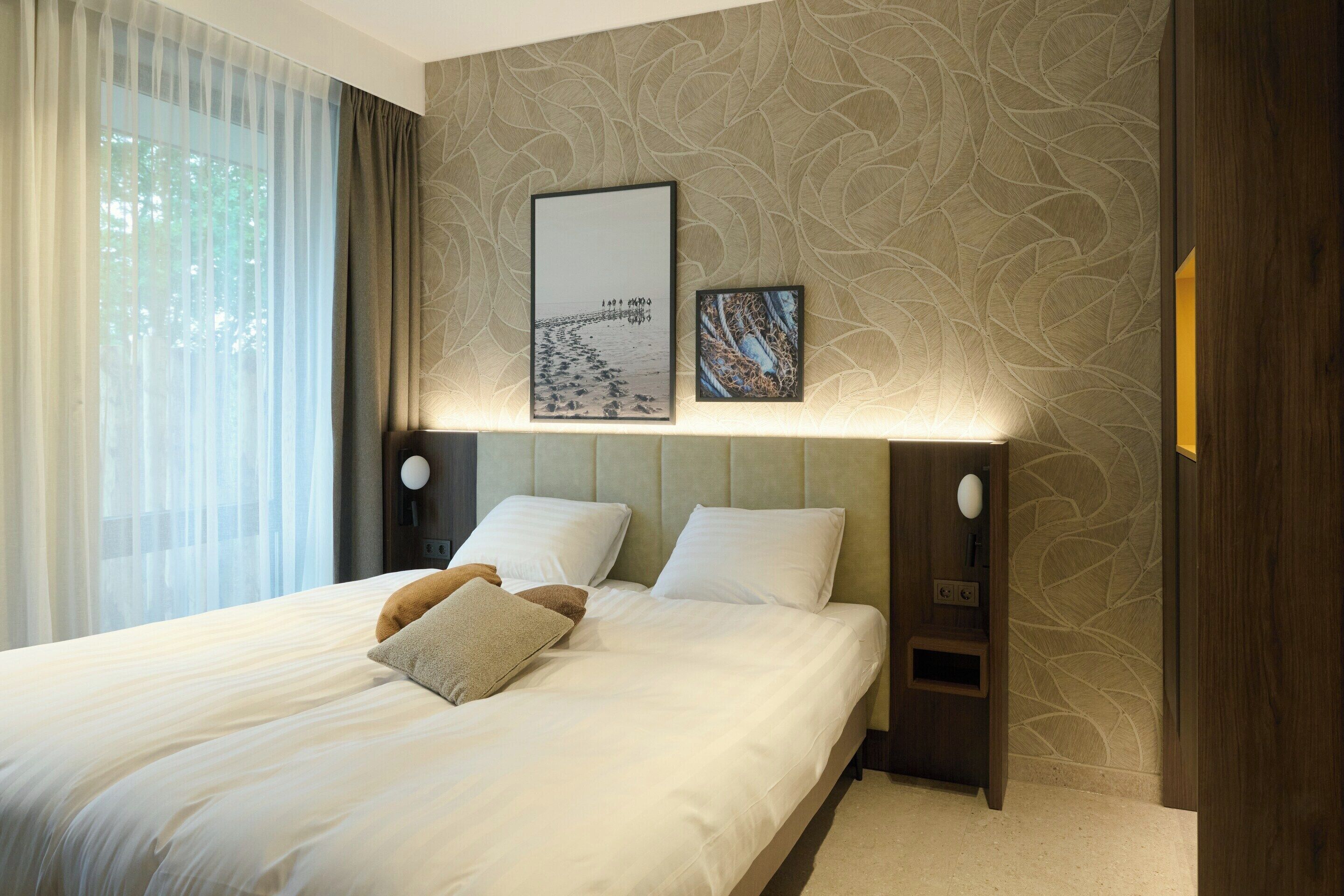 A neatly made bed with pillows, a headboard, and wall-mounted artwork.