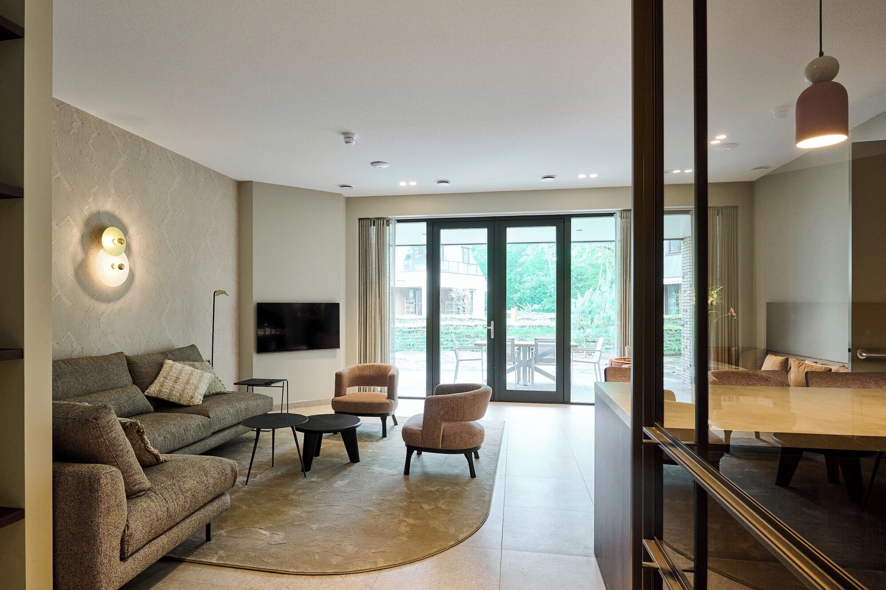 A modern living room with a sofa, chairs, a coffee table, and a TV.